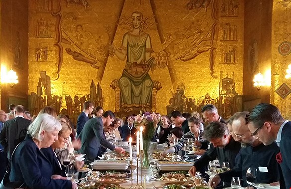 A picture from a dinner in the City Hall with a large golden wall in the back. 