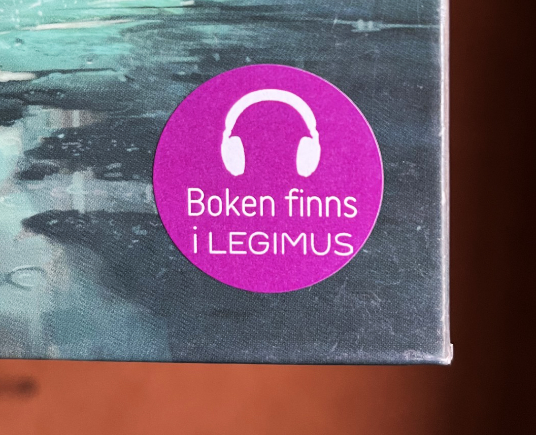 Klistermärke med texten Boken finns i Legimus sitter på en bok.