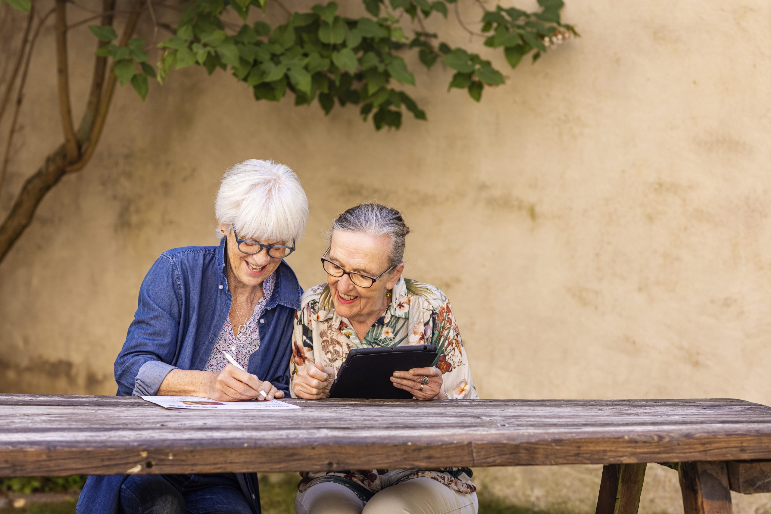 Två kvinnor läser tillsammans utomhus