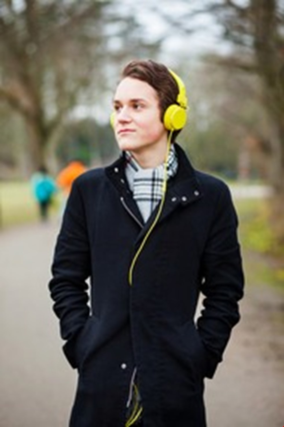 En ung man har på sig hörlurar och är ute och går i naturen