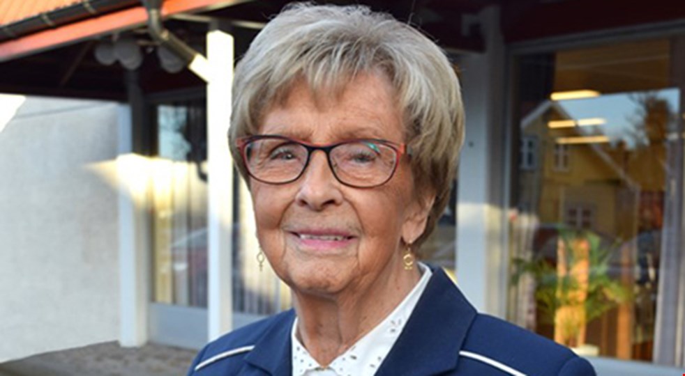Årets läsombud 2023 Ulla Borgius står framför en bokhylla. Hon är klädd i en blå kavaj.