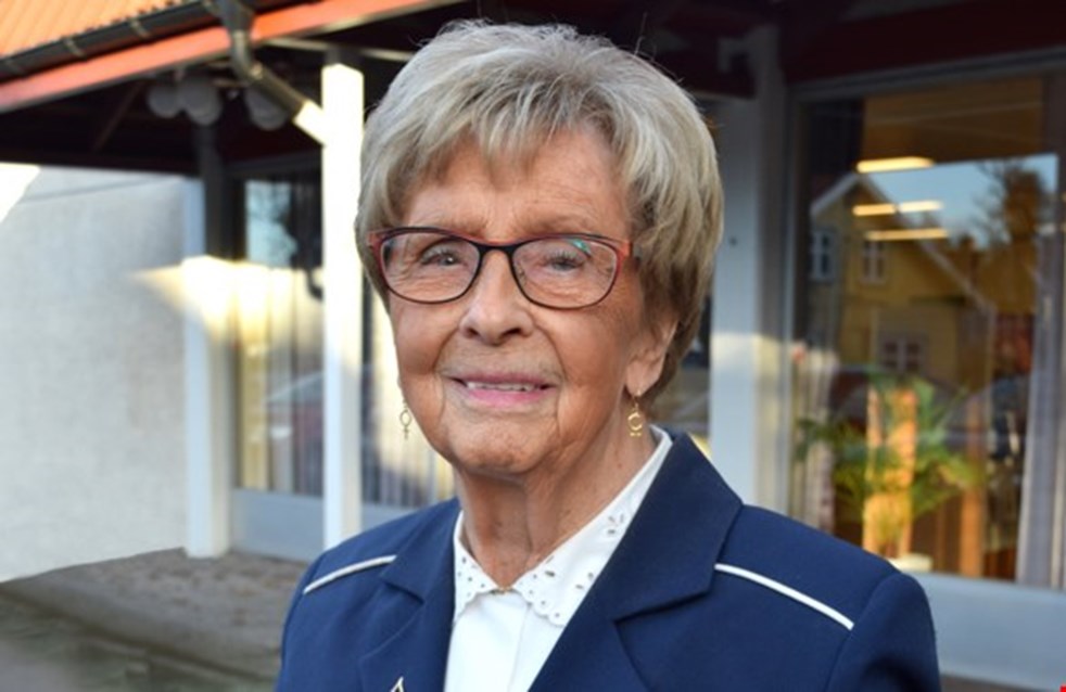 Ulla Borgius är Årets läsombud. Hon står framför en bokhylla och är klädd i blå kavaj.