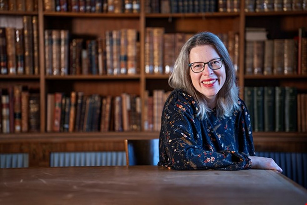 Lynn Alpberg, vinnare av Läsguldet, står framför en bokhylla.