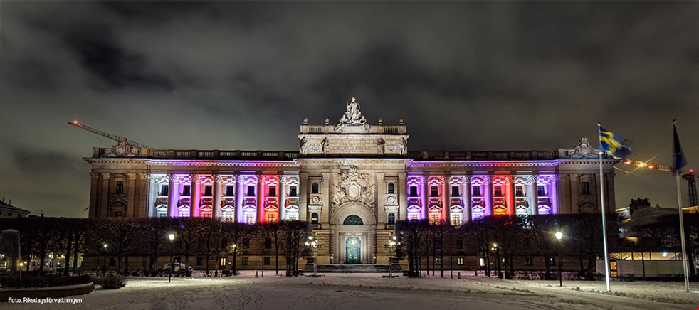 Bilden visar när beslutet om allmän och lika rösträtt uppmärksammas med ett ljusspel på Östra riksdagshusets fasad, den sida som vetter mot Norrbro. Foto: Riksdagsförvaltningen