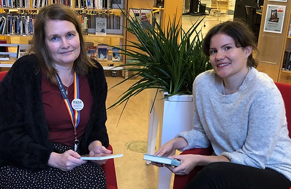 Kajsa Bergh och Maria Lorentzon är  Årets läsombud. De sitter i fåtöljer på ett bibliotek. Kajsa till höger och Maria till vänster. Kajsa har en röd tröja. Maria en grå.