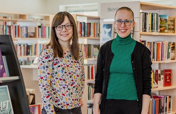 Porträtt- /kroppsbild på Sanna Barsk och Malene Jensen. I bakgrunden syns bibliotekshyllor fyllda med böcker.