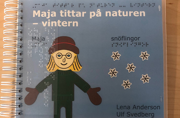 Omslag till boken Maja tittar på naturen - vintern. Maja står i grön tröja och en brunhatt framför en blå vinterhimel.