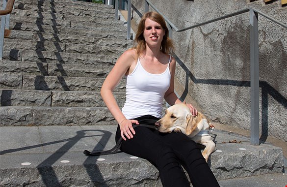 En kvinna som sitter på trappan med en hund i knäet